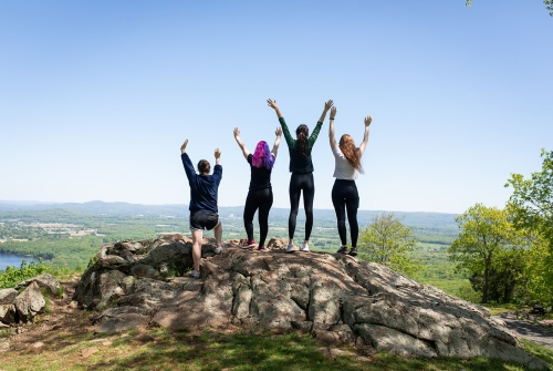 Four seniors cheering with arms raised at the top of ŷAV